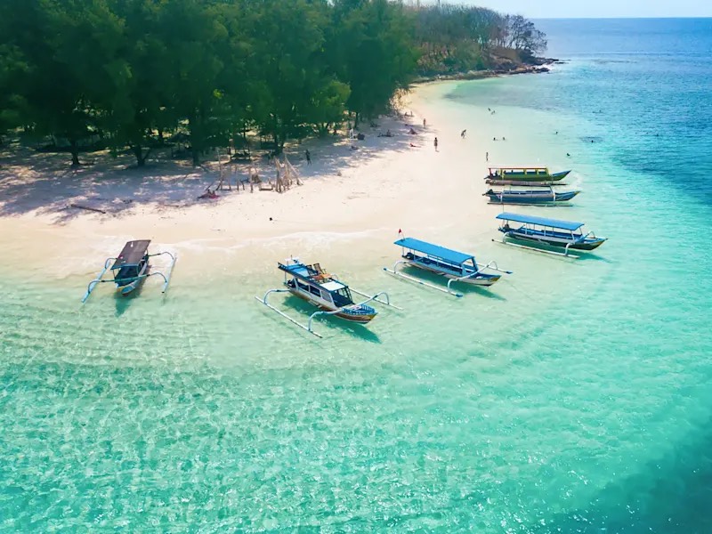 Bali : pirogues à balancier amarrées le long d'une plage de sable blanc, sur une eau turquoise